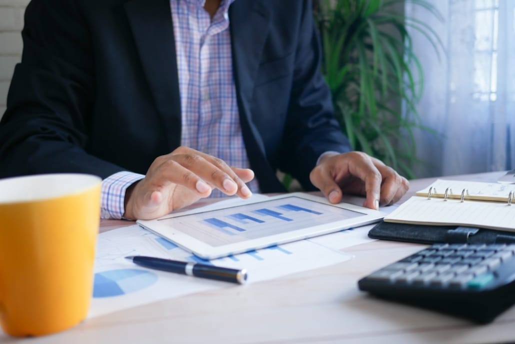 Un dirigeant senior seul ou en petit comité, en situation de réflexion face à des documents financiers ou un écran d'analyse. Ambiance sobre, lumière naturelle ou tamisée, environnement bureau moderne. L'image doit transmettre le doute sérieux, pas l'échec — la pensée stratégique, pas la détresse.